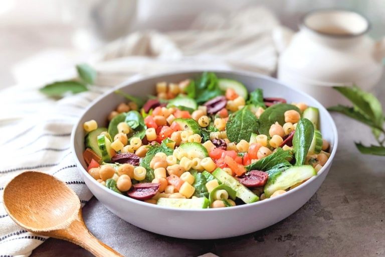 a big bowl of vegan pasta salad with ditalini noodles cucumber spinach tomatoes and olives in a red wine dressing for pasta salad.
