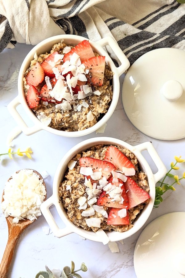 high fiber oatmeal for breakfast in two bowls topped with strawberries coconut flakes and chia seeds