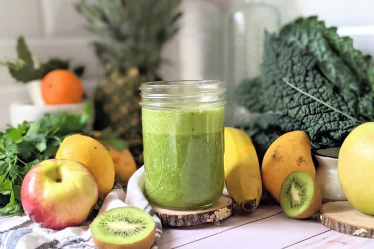 green smoothie with kiwi spinach apples pineapple kale mango and green goddess juice in a blender, vegan and gluten free.