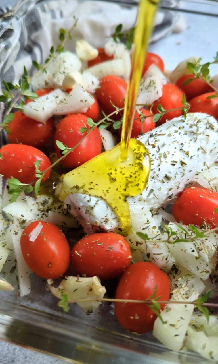 goat cheese drizzled with olive oil and tomatoes and fresh thyme in a baking dish tiktok pasta with goat cheese